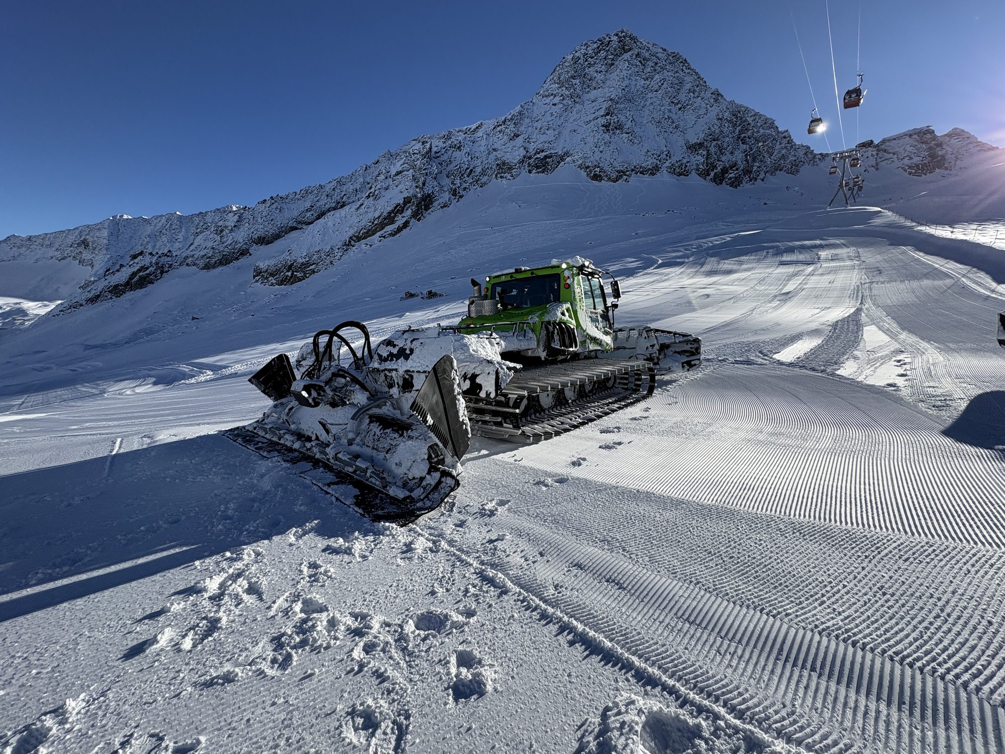 PistenBully 600 E+ at golden hour with alpine peak